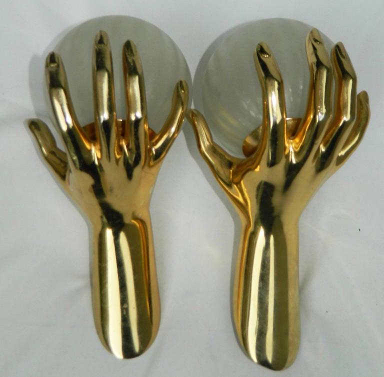Maison Lancel pair of sconces, featuring a pair of gold hands holding a lighted class globe.
US wired and in working condition.
60W/bulb.