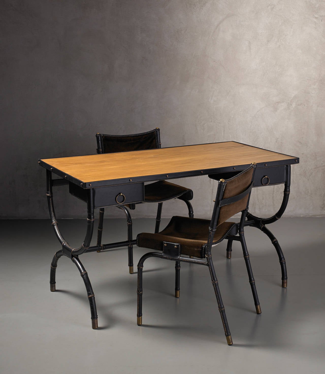 Desk and two chairs by Jacques Adnet 
France, 1950-60
Black leather covered frame, oak wood top, pull out drawers