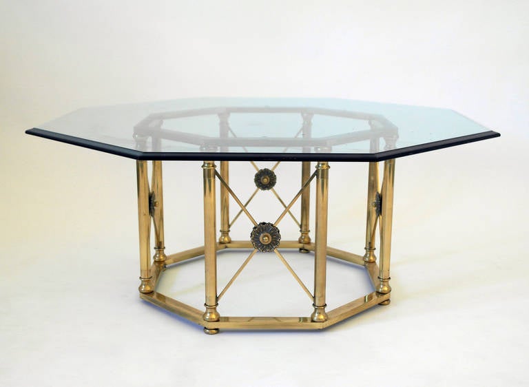 Mid-century brass coffee table circa 1960s. Eight sided base in high polish brass featuring floral motifs set on "X" design with a beveled glass top.
