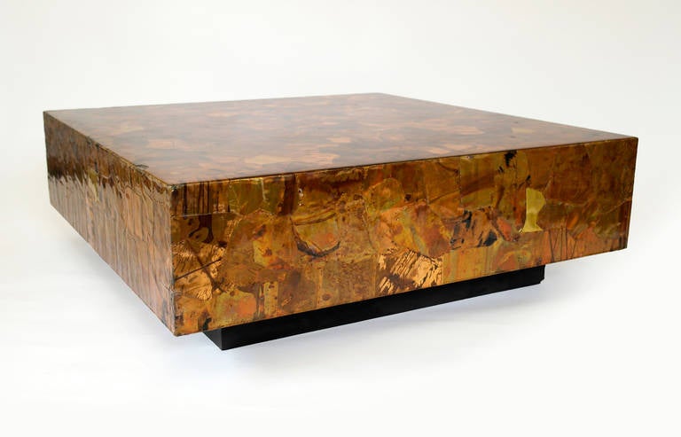 Low box coffee table in the style of Paul Evans. Patchwork design comprised of abstract copper and bronze metal layers with heavy lacquered finish on contrasting black plinth. Unsigned.
