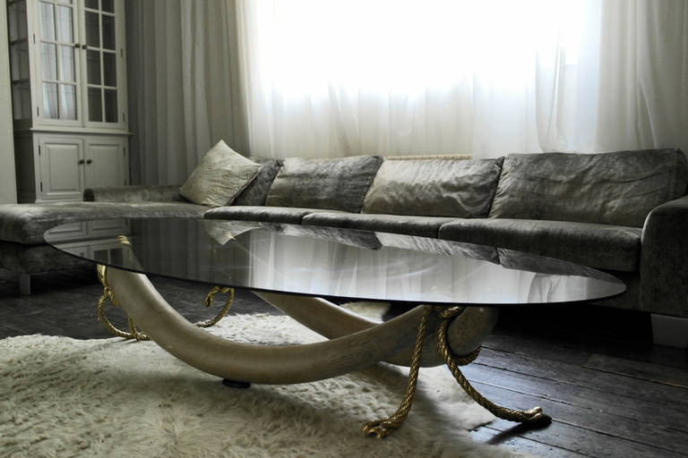 Beautiful low coffee table comprised of oval smoke glass on moulded resin elephant tusks, featuring decorative brass rope mount. A striking late 1970's piece, unsigned but the design is attributed to Italo Valenti.