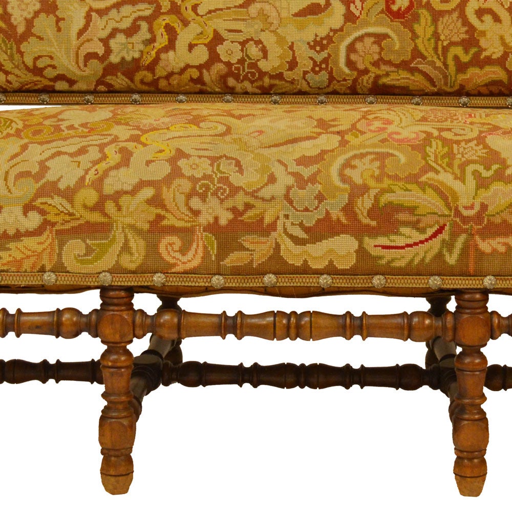 English Lancashire County Country settle upholstered in the original needlepoint tapestry with a beautiful design motif in greens, golds and browns. This settle is very sturdy, constructed in solid walnut. Measures: Seat depth: 25