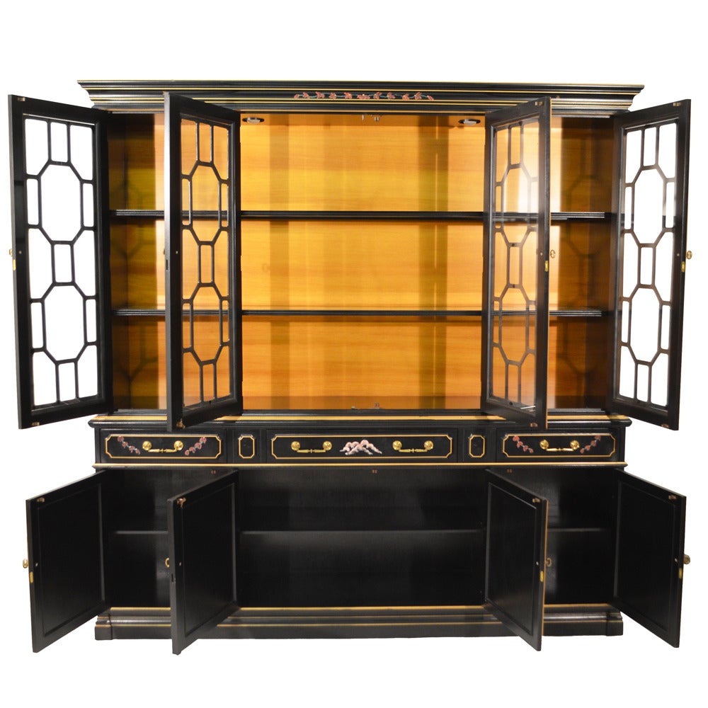 Black lacquered breakfront featuring hand-painted chinoiserie, garden scenes with pagodas and people. Filigree wooden glass insets, three drawers, four doors, shelving behind doors. Breakfront has two lights on either end for lighted display; keys