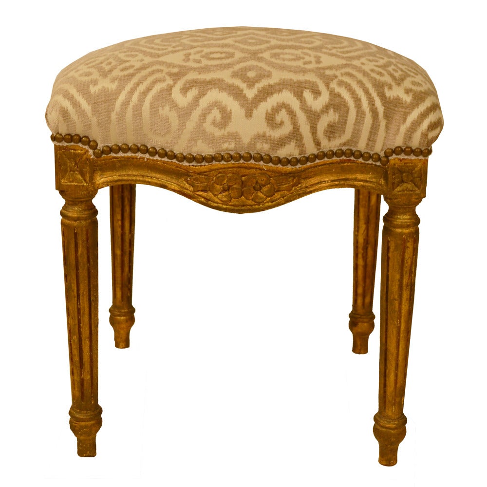 Pair of gilded Louis XVI stools with fluted legs, newly upholstered in a burned out taupe and cream fabric. Hand carved with a classical motif French design.