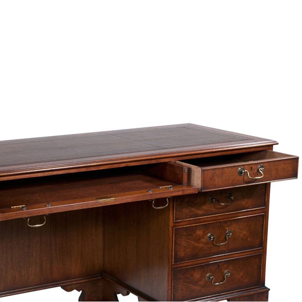 Chippendale style walnut credenza with a tooled gold inset and brown leather top, double file drawers and bracket feet.