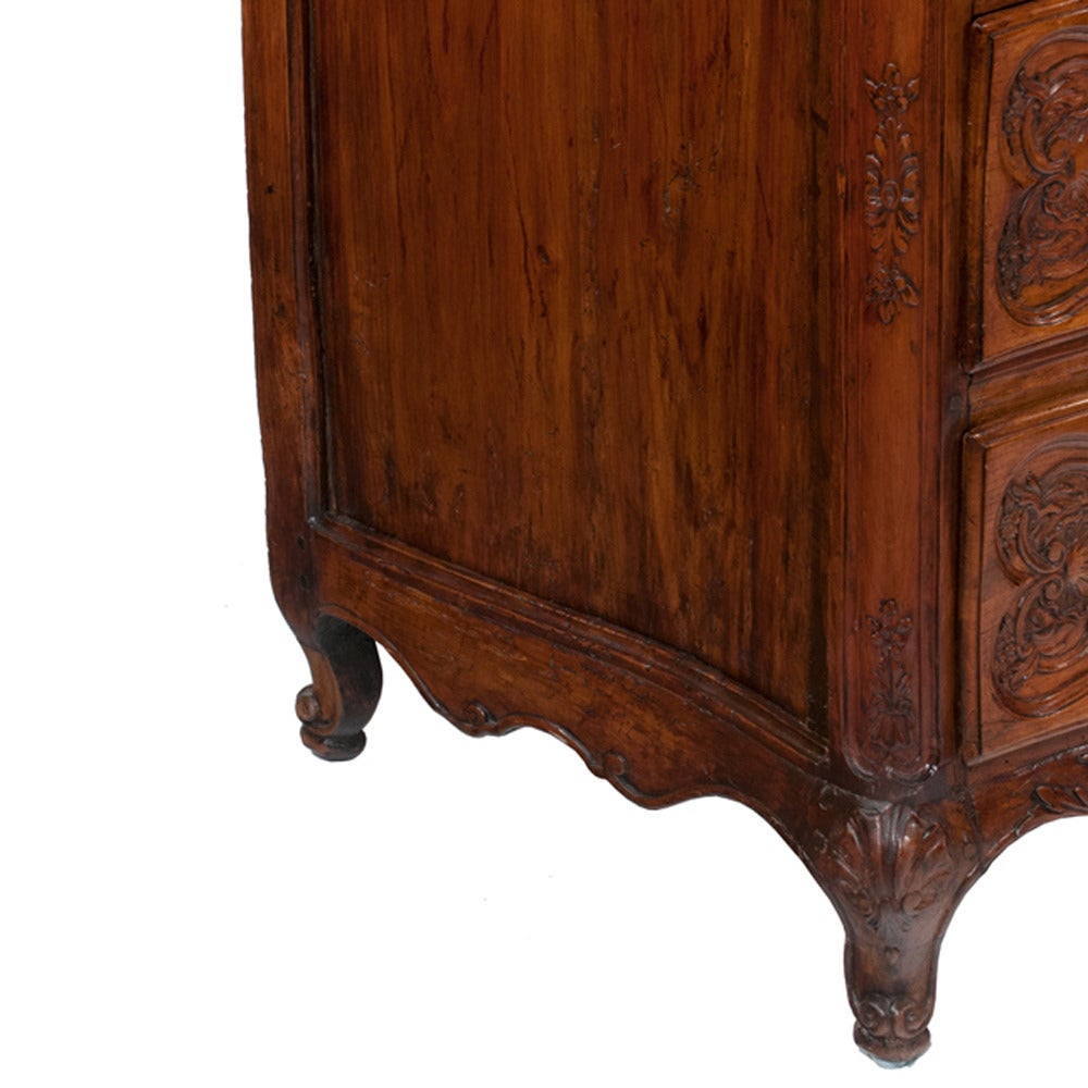 Chestnut and oak serpentine front country French commode with carved drawer front and carved apron, circa 1830. Original antique brass pulls and keyholes add detail to this beautiful commode.