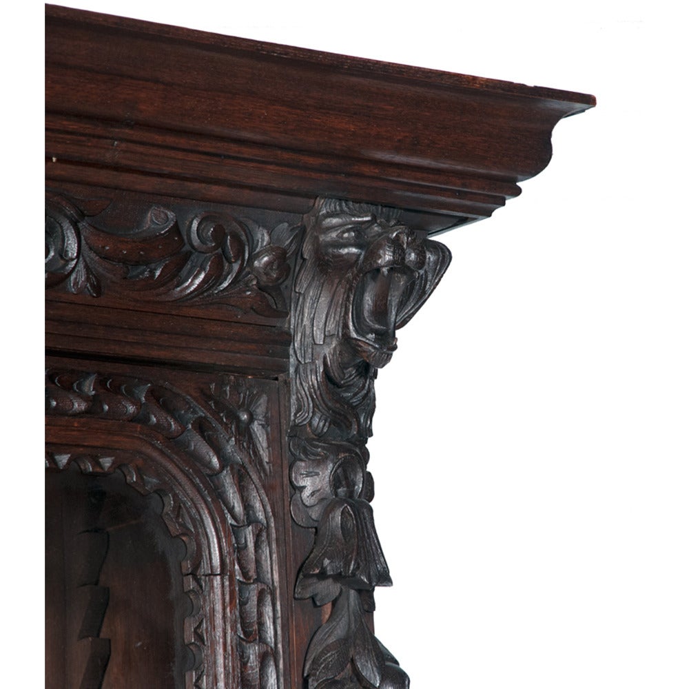 Solid oak Country French lodge cabinet features double glass doors with three shelves behind on top as well as double doors with single shelf on bottom unit. This cabinet also has very intricately hand-carved lion's heads on the corners, as well as