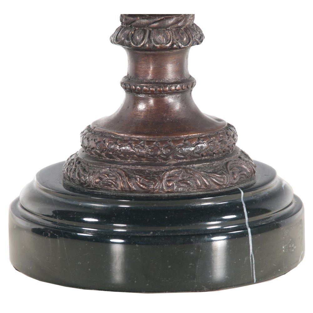 Pair of French bronze urns with dome lids and scroll handles on marble bases...intricately detailed with a very classic French motif.