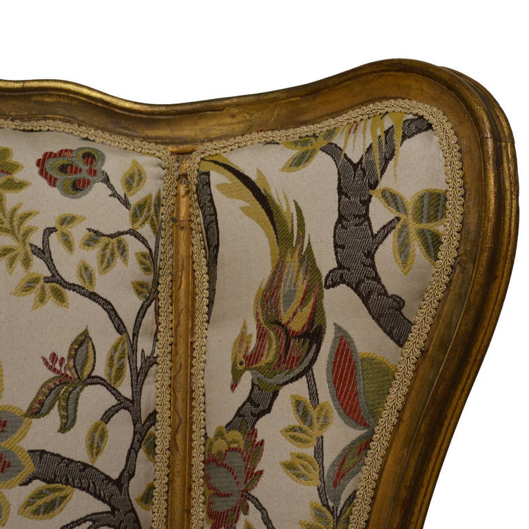 Pair of exceptional Louis XV bergères upholstered in a French brocade fabric, featuring a bird and floral scene. Gold gilded finish with hand-carved detailing and new upholstery. In pristine condition, circa 1895.