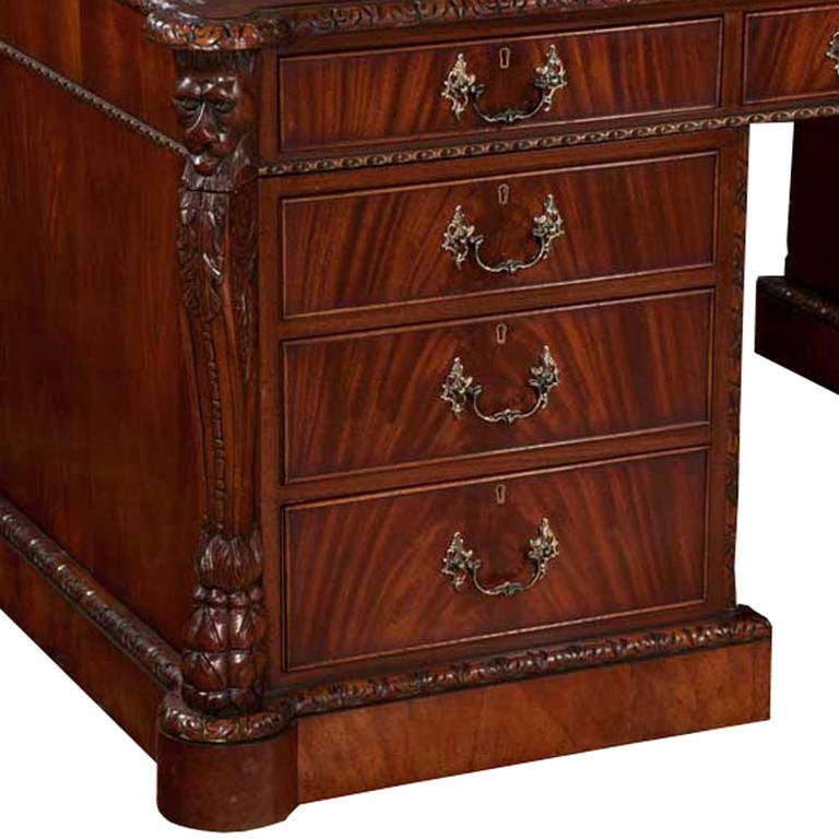 Exceptional Chippendale solid mahogany partners desk with lions head carved detailed corners and a carved molded base. The working surface features a hand tooled leather top. Center lap drawer is flanked by two sets of drawers providing ample