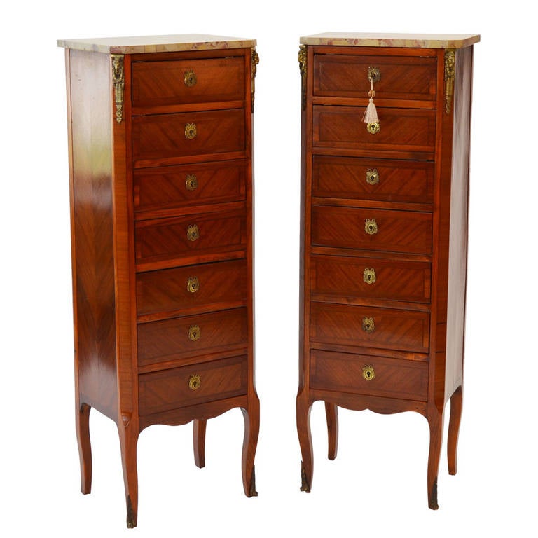 Superb pair of bronze mounted French Semainiers in the style of Louis XVI featuring the original cream with brown breccia marble tops above kingwood inlaid drawers. The seven drawers feature antique bronze keyholes for access. Circa 1895