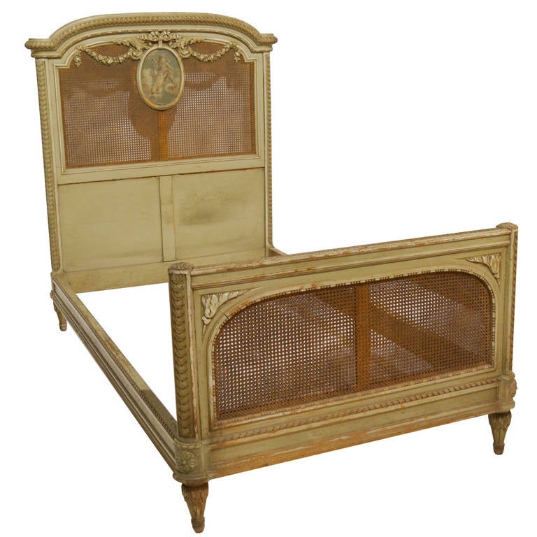 Pair of Louis XVI-style painted twin-size beds with carved and cane-paneled headboards and footboard, circa 1900.