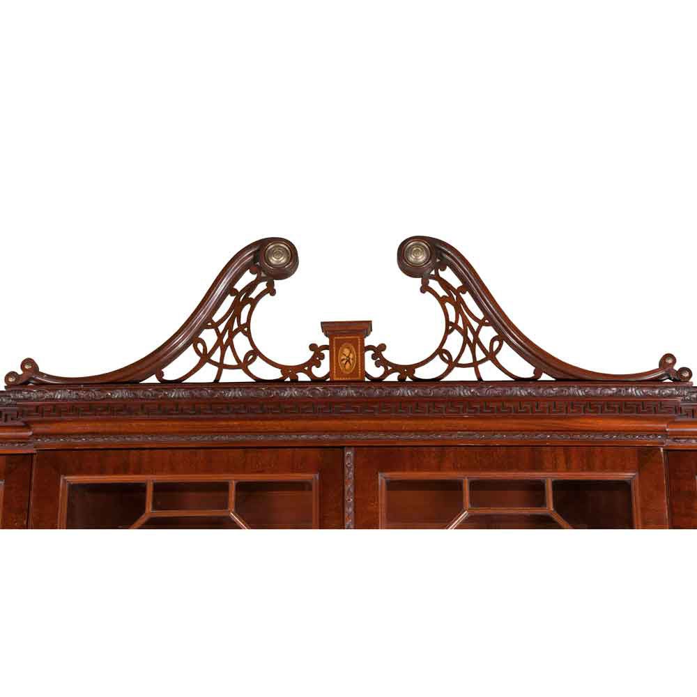 Chippendale solid mahogany breakfront or bookcase with a pierced broken pediment, Grecian key crown molding, mullion glass doors, and a base that features a scrolled apron on cabriole legs with ball and claw feet.