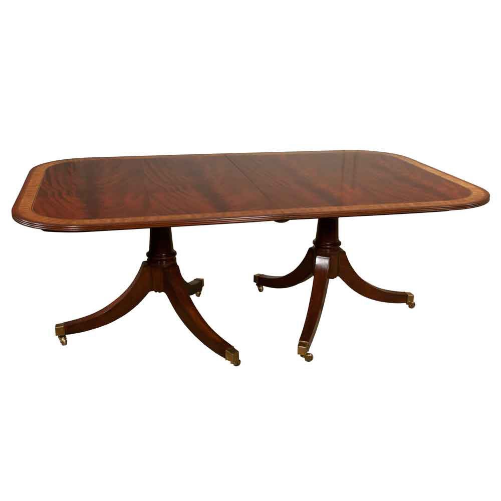 Two pedestal, solid mahogany dining table with satinwood banded top, pedestals have turned columns and three splay legs with brass casters. Has 2 24