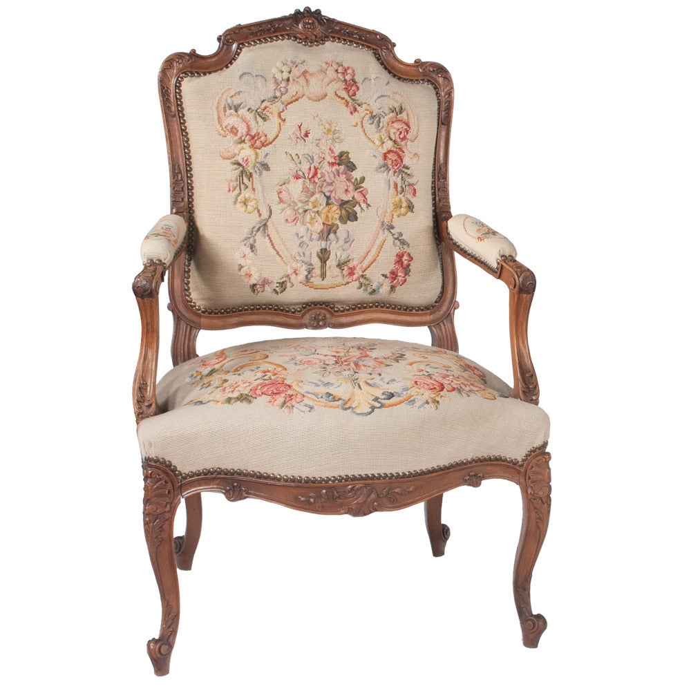 Pair of Louis XV-style hand-carved walnut fauteuils covered in a floral needlepoint tapestry. Circa 1900.
