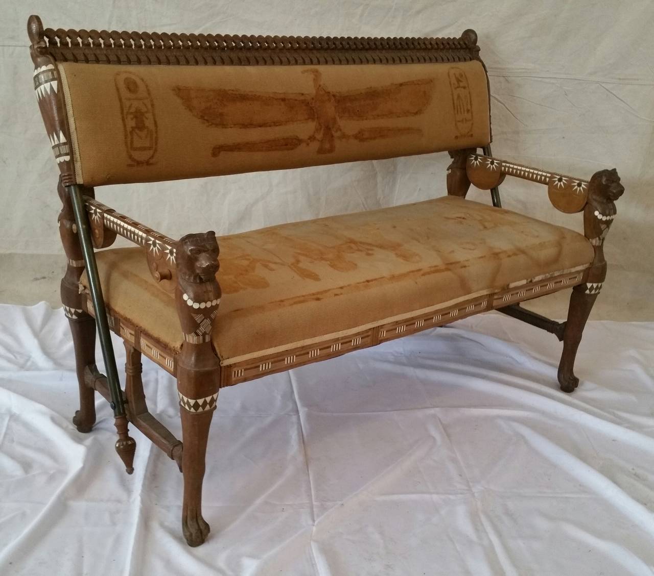 Egyptian Revival loveseat composed of rosewood inlaid with bone,ebony ,,Upholstered in a burlap fabric in Egyptian motif,,original,The loveseat features reversable back and decorative Egyptian carvings,,Similar example can be found in the Victoria &