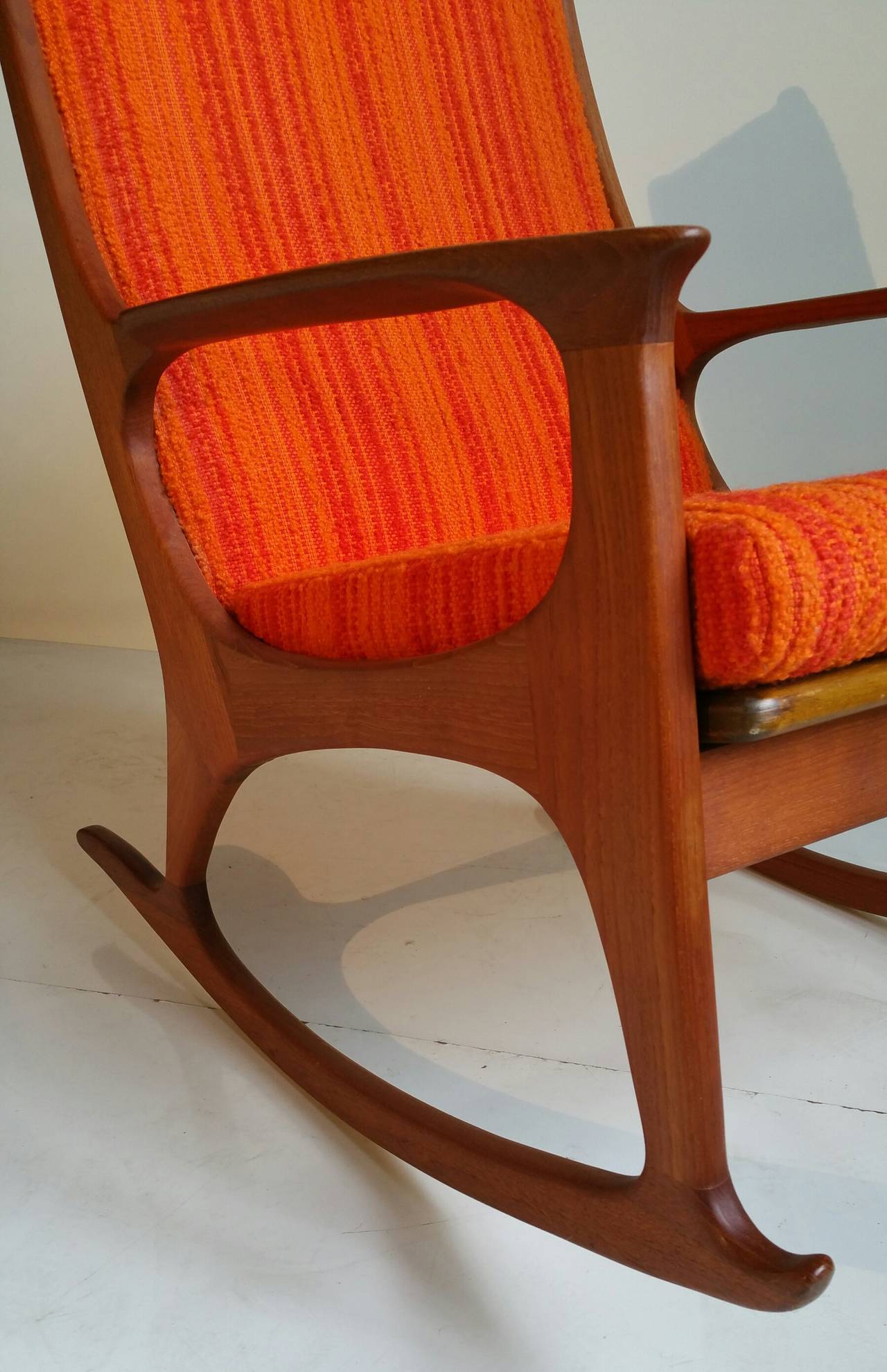 Beautiful curves and elegant craftsmanship adorn this vintage rocker, made of solid teak with exquisite joinery. Made in Denmark. Retains original Scandinavian orange striped wool fabric excellent original condition. Extremely comfortable.