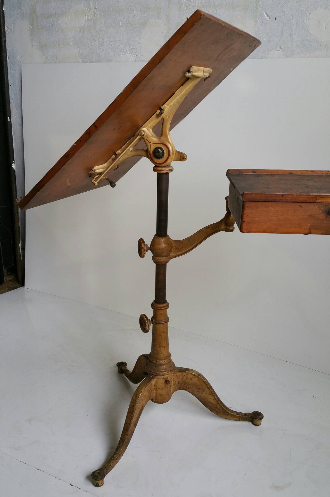 Turn of the century fully adjustable drafting table, top measures 27 x 21, heavy cast iron base, beautiful paint and surface, Retains seldom seen swivel drawer. Measuring 15 x 11. Beautifully proportioned.