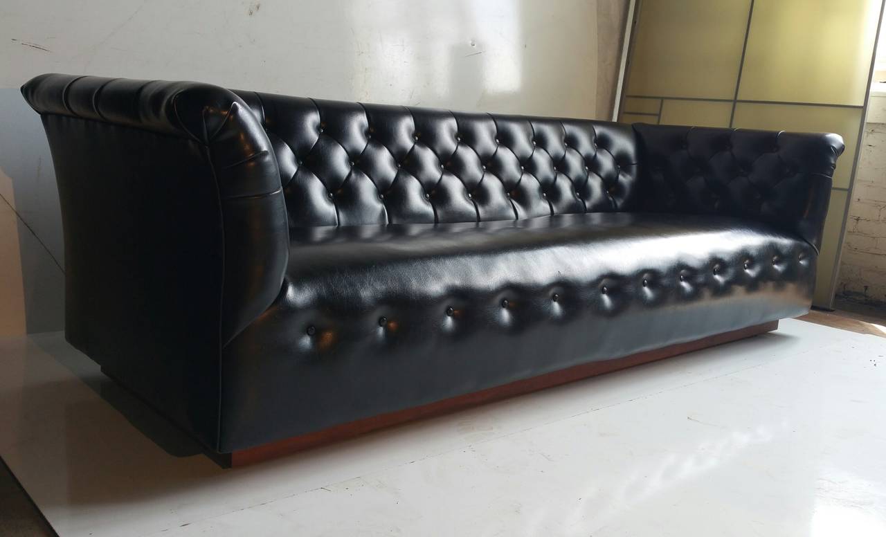 Stunning modernist sofa designed by Milo Baughman for Thayer Coggin. Retains original black naugahyde fabric. Beautiful original condition. Appears to be floating a top walnut plinth, with castors.