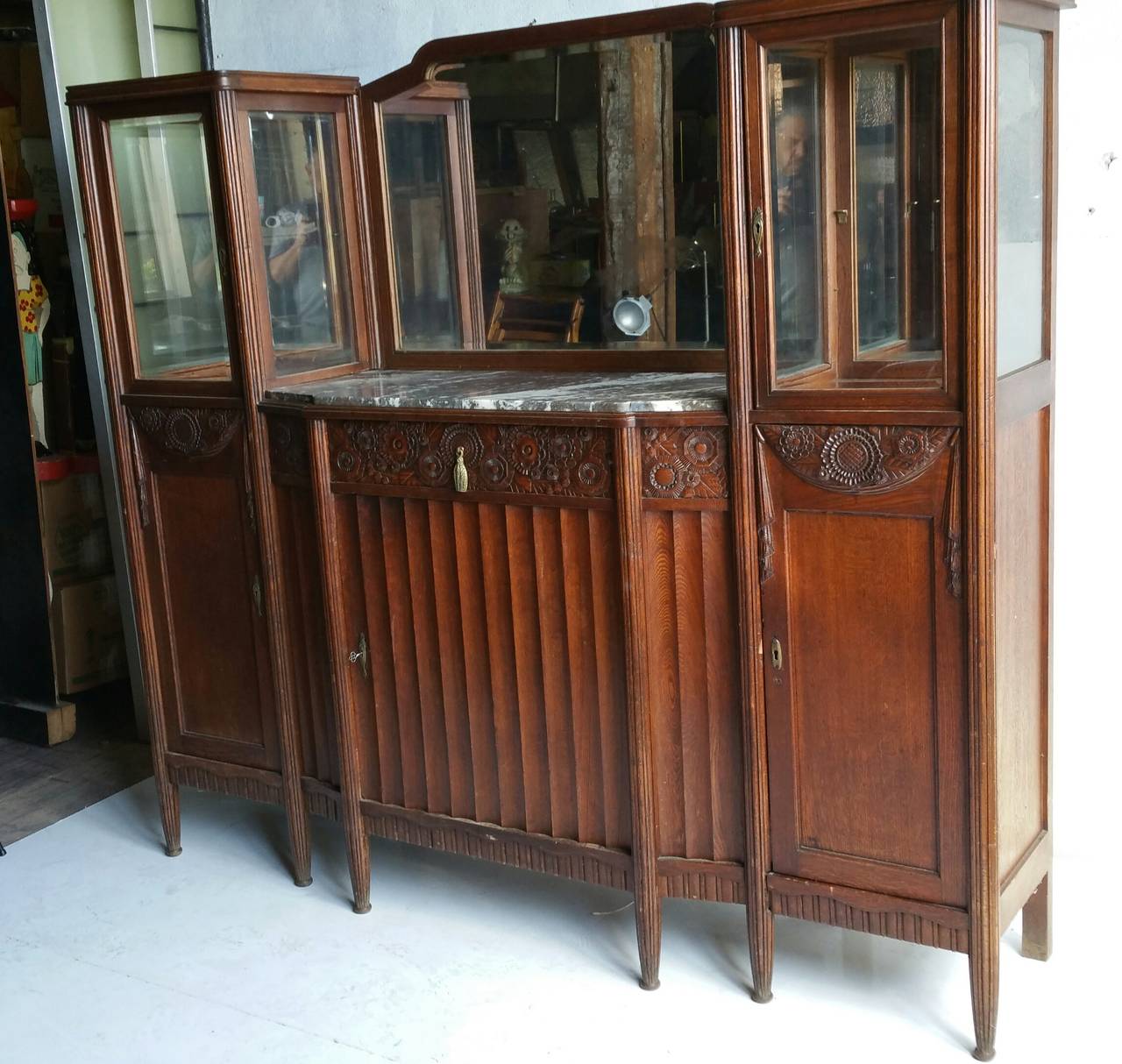 Exquisite French Art Deco Cabinet,, Carved wood and bronze detailing reminiscent of Paul Fallot's designs,,Features center beveled mirror and  beveled glass cabinets. Also retains original grey and white marble top..Classic French fluted legs,