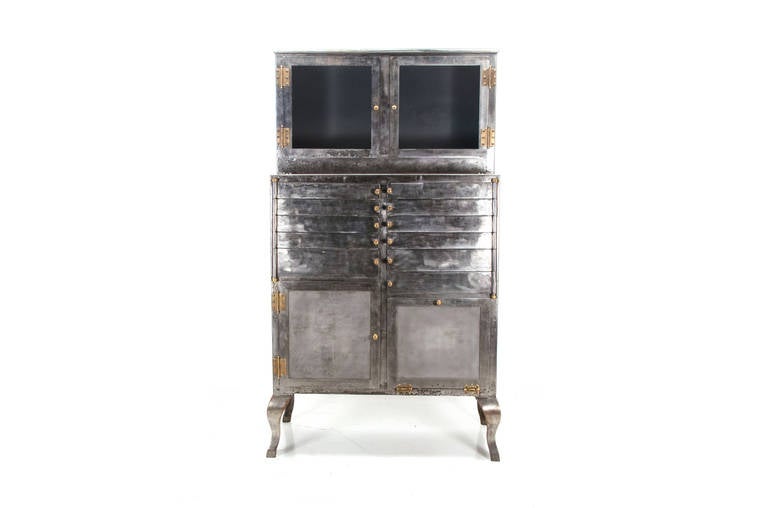 Industrial metal medical cabinet , newly restored in a rough Machine Age style finish. Multi-drawer, pie-shape shelves behind two doors on top, storage on bottom. The unit has been stripped, sanded, and lacquered to accommodate your kitchen,