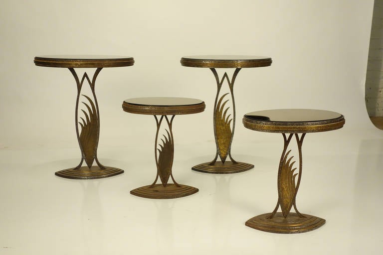 Set of four Art Deco display tables. In the manner of Edgar Brant. Beautifully decorated, gilt metal, brown smoke glass. Two matching pairs.
One measuring 12