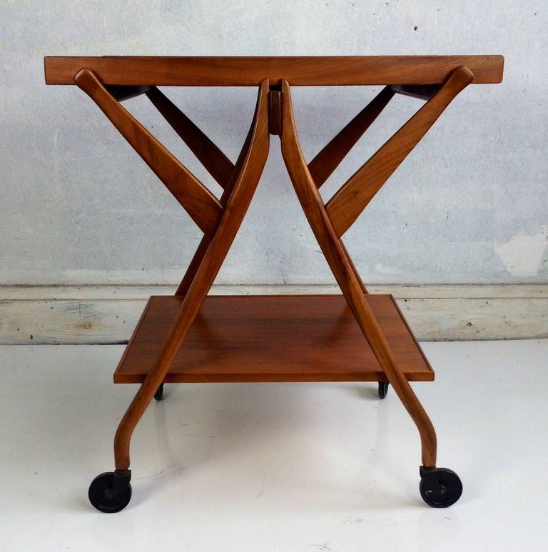 Sculptural walnut modernist serving cart or table. Amazing design. Removable tray top. Original stylized casters,