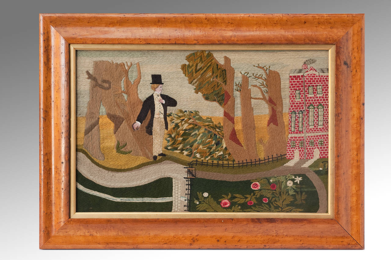 A folk-art woolwork picture depicting a scene within a parkland setting of a country gentleman (who is entirely stitched in silk) standing before a red brick country house that is enriched with a formal rose garden enclosed by iron railings and a