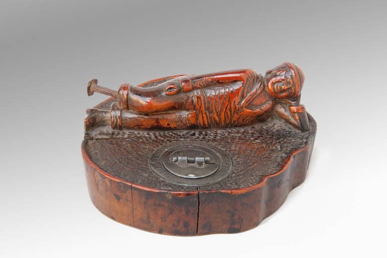 An early 19th century inkwell stand carved from a single cross-section of Cherry wood now matured to the most fabulous color and patina. It features a sailor with a peg-leg, rolled up trousers and a beret and an expression that implies he has come