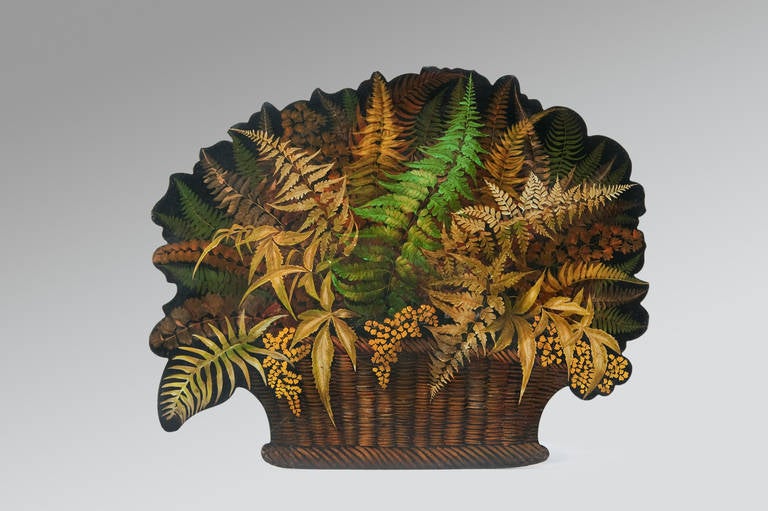 A Painted and lacquered papier-mâché Chimney-Board on a black ground, having a botanical theme with an arrangement of various ferns emanating from a weaved basket.
