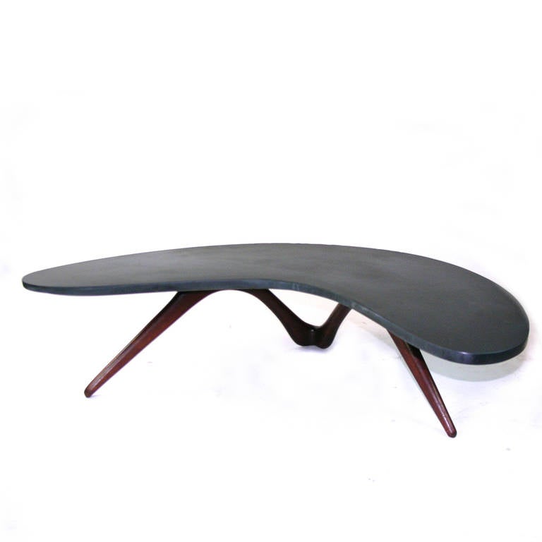 A  Vladimir Kagan-Dreyfus  (Boomerang) table with a undulating leg in solid walnut. The original top is black honed slate with some chipping on the back edge that could be filled. Also available from Kagan at the time was Travertine and Carrera