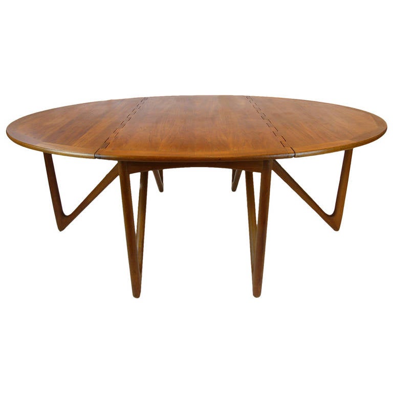 Teak sculptural base table designed by Kurt Ostervig for Jason Mobler. Six triangular legs support the table. End legs swing out to support the leafs. The table can be compact or fully extended to seat eight.