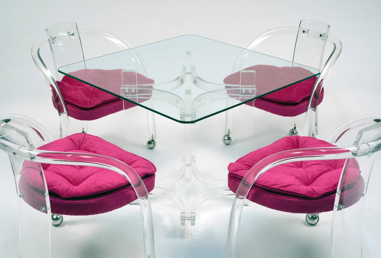 Clean set of ultra chic four lucite chairs. Set comes complete with hard to find matching lucite table base with glass top.  Chairs have been professionally reupholstered in hot pink/fuchsia chenille upholstery. Casters on chairs are original. 