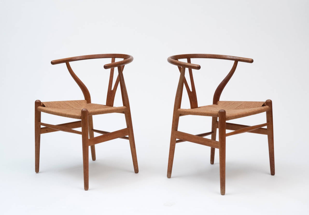 A nice pair of oak Wishbone chairs by Hans Wegner for Carl Hansen & Son.  Chairs retain the original paper cord seating and branded mark.