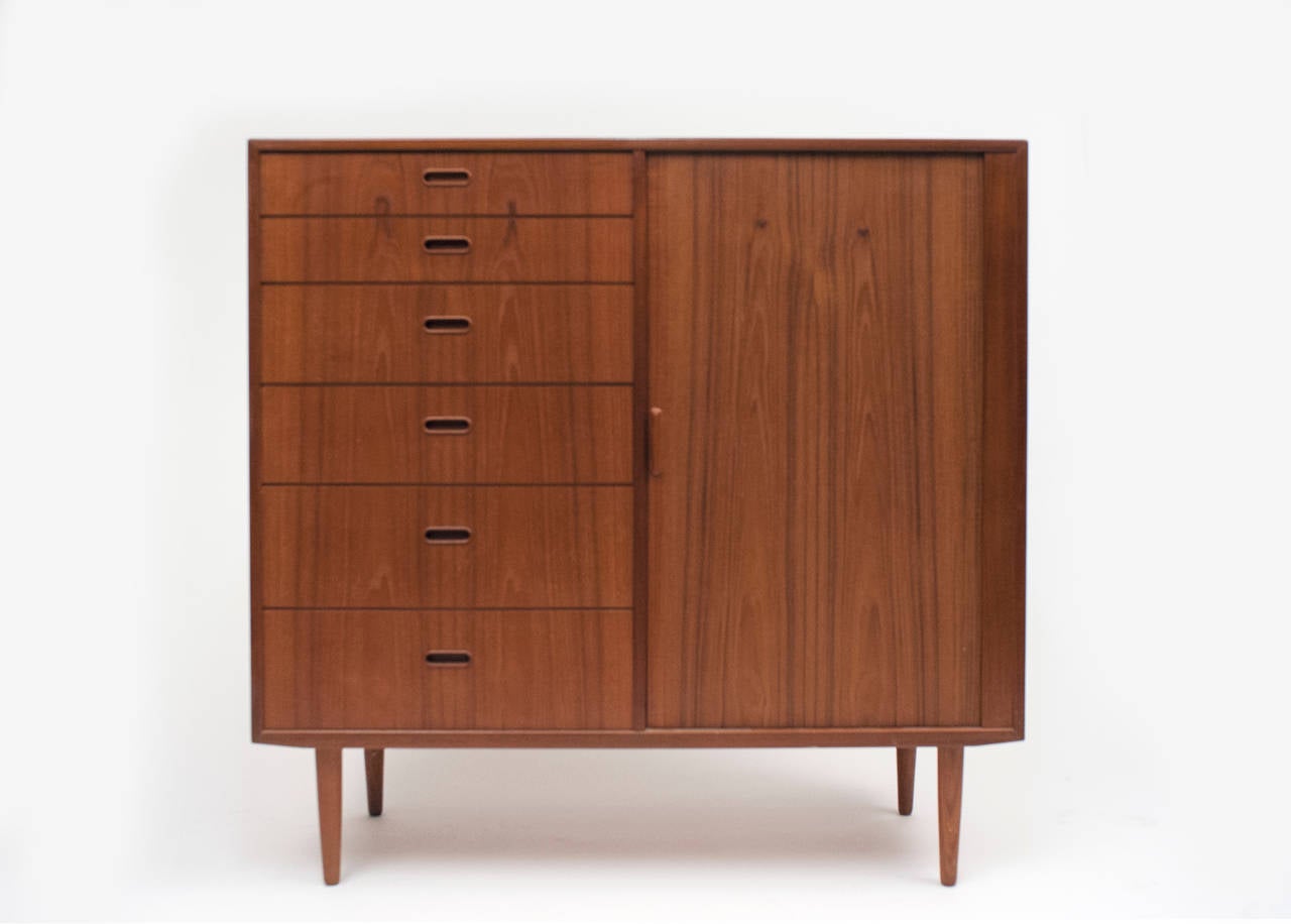 Well constructed chest of drawers by Danish manufacturer Falster.  Cabinet is in excellent condition with original patina and striking teak grain. Twelve drawers allow for ample storage.  Tambour door slides with ease.  