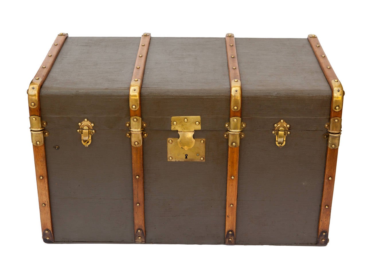 A striking, refurbished antique French trunk that has been lovingly restored inside and out. Its flat top makes it perfect for a coffee table, and the contrast of the wood and brass against the grey is drop dead gorgeous!