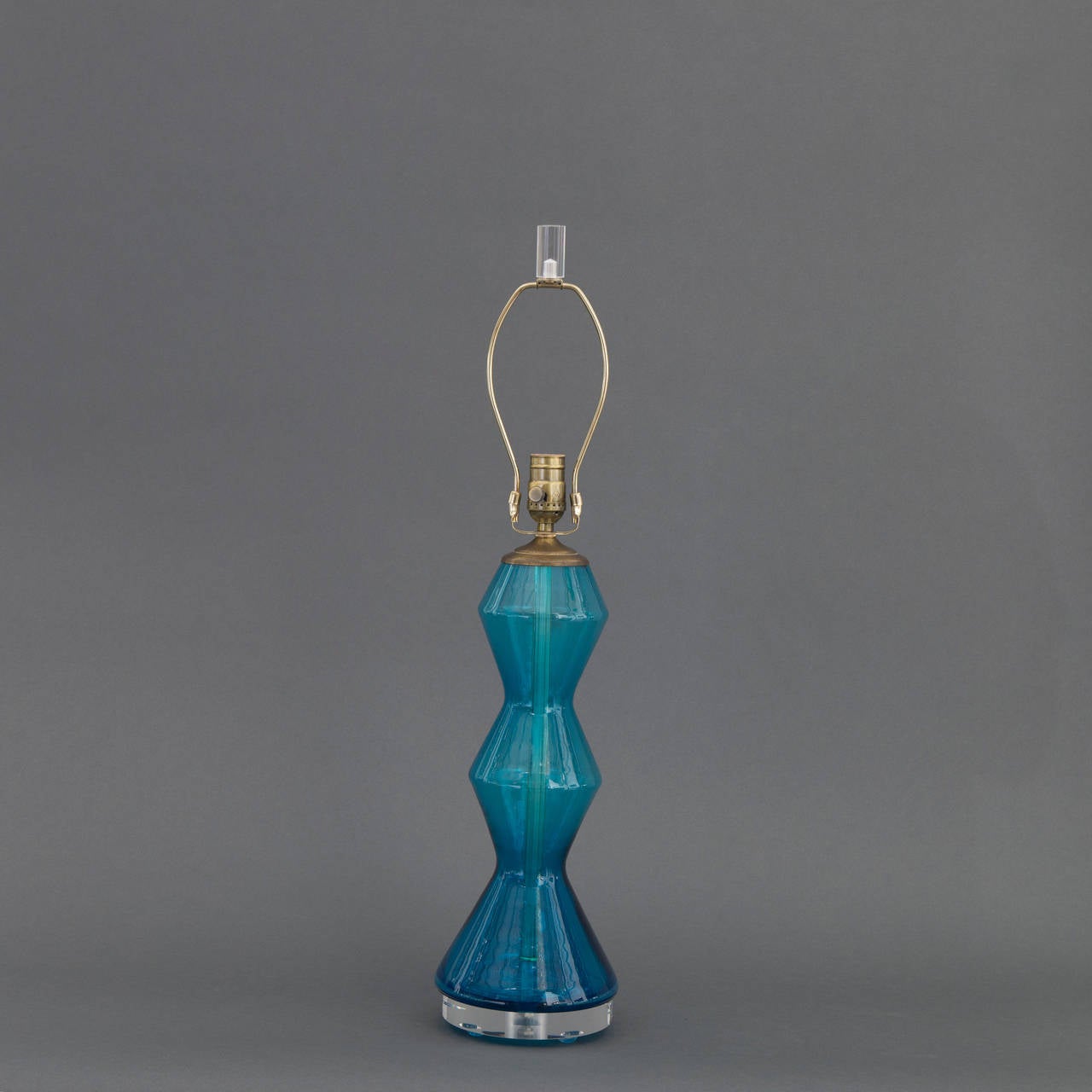 This beautiful goemetric hand blown Muran glass lamp is a most unique shade of blue falling somewhere between teal and acqua. We have added the Lucite bases for an updated luxe look. The lampshade is not included; however, can be purchases at