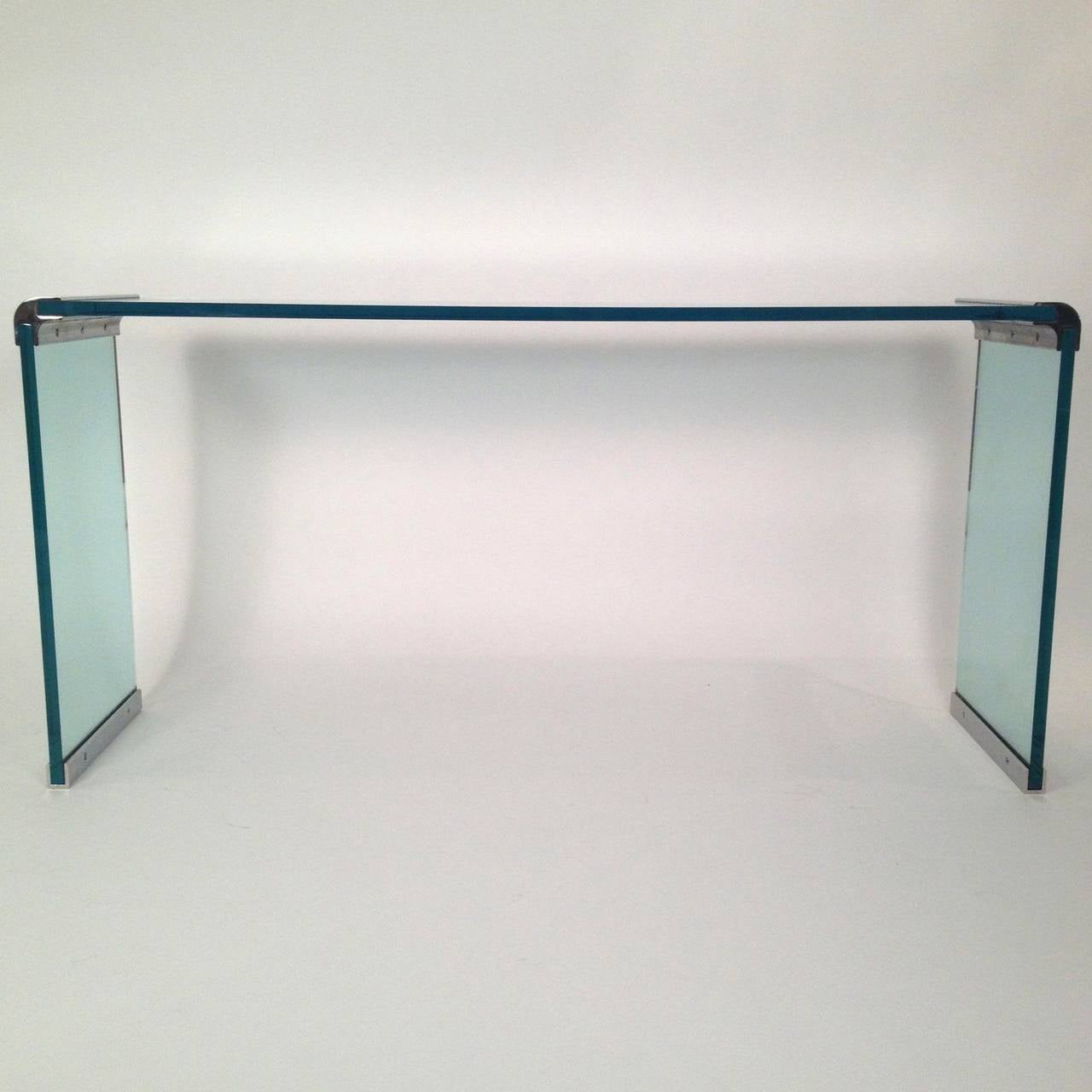 Offered is a sleek and modern console table in glass and chrome with the simple yet elegant look that is a Pace design signature.  The console offered is rare in that it has the chrome joints at the top and the chrome bases at the bottom.