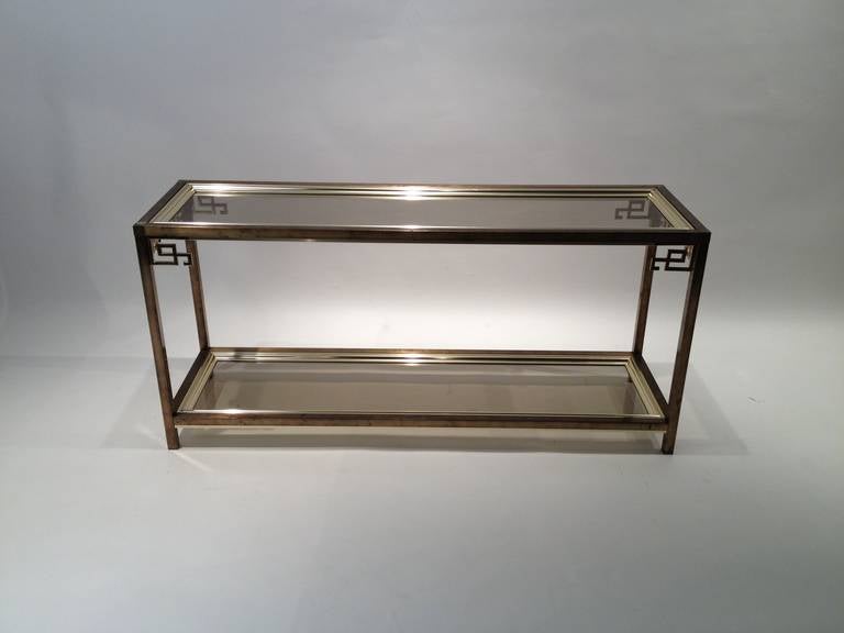 Glamorous brass and glass Mastercraft Greek key console or sofa table. Matching Mastercraft Greek key side table also available. Fashion forward brass key accents around the top layer of glass and brass hovers above the base. Perfect for an