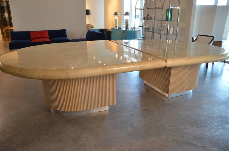 Offered is a Mid-Century Modern monumental clear lacquered goatskin dining table with a fluted wood and metal accent base by Steve Chase. This breathtaking dining table has been restored and in very good condition. The two bases are wood; carved