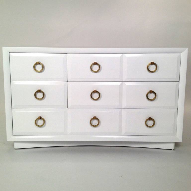 Five-drawer dresser by Robsjohn-Gibbings for Widdicomb newly lacquered in white. Amazing solid wood construction and thick solid brass pulls. Bottom front has an elegant arched base.