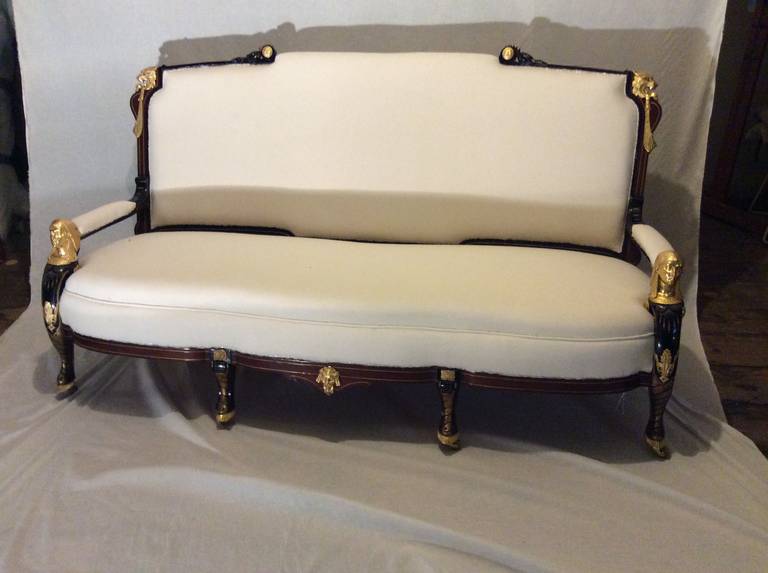 Egyptian Revival Settee. Gilt incised, ebonized mahogany with bronze dore mounts depicting sphinx, lions, heads, and mask. Stylized Pharo's beard as leg terminating in a hoof.
With the opening of the Suez Canal. circa 1870, once again the Egyptian