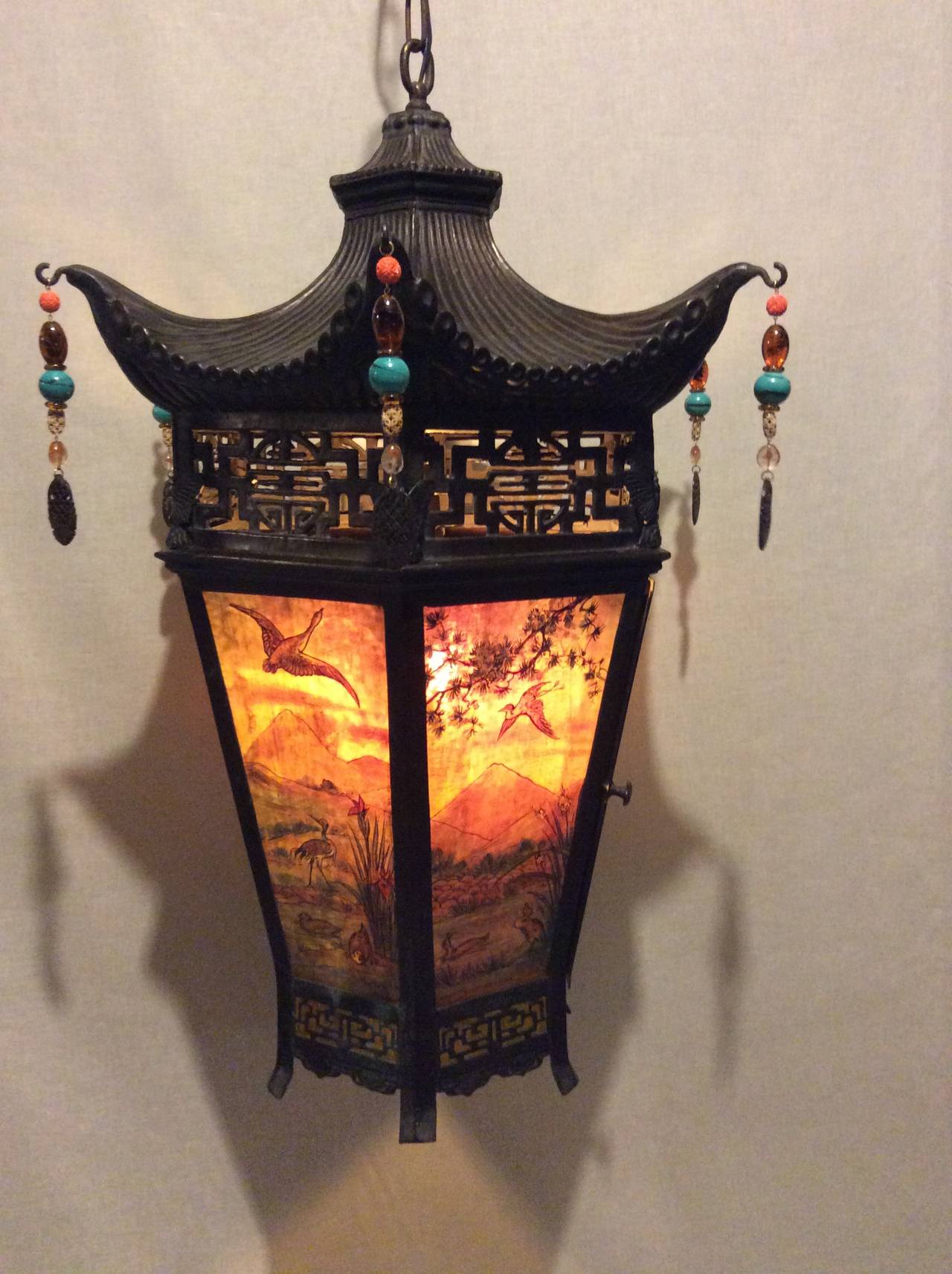 Arts & Crafts oriental style hanging lantern.
Scenic landscape painted and stained glass panels (six)
(similar to handle lamp shades) as features for this large, impressive lantern. Made of copper which has been pierce carved with oriental design