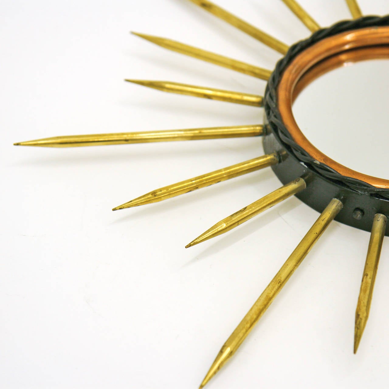 Unique vintage sunburst mirror from France made of three different metals: A black lacquered iron belt with wrought detailing, a copper ring on the inside and solid thick brass 