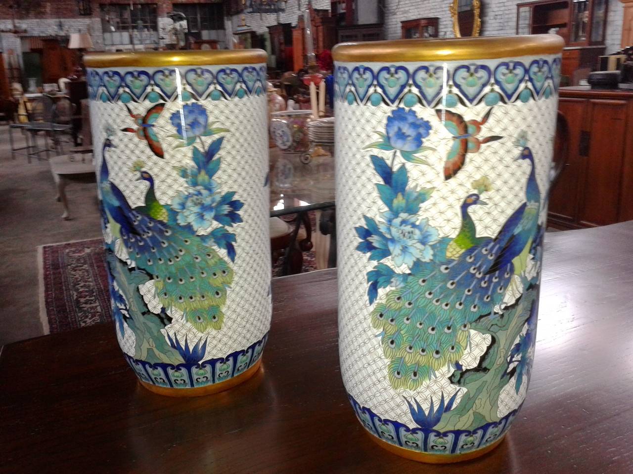 This circa 1880s cloisonné peacock floral vase or umbrella stand in enamel and brass are very beautiful. Striking with the butterflies, peacock and floral scene accented by the turquoise inside and a gold rim.