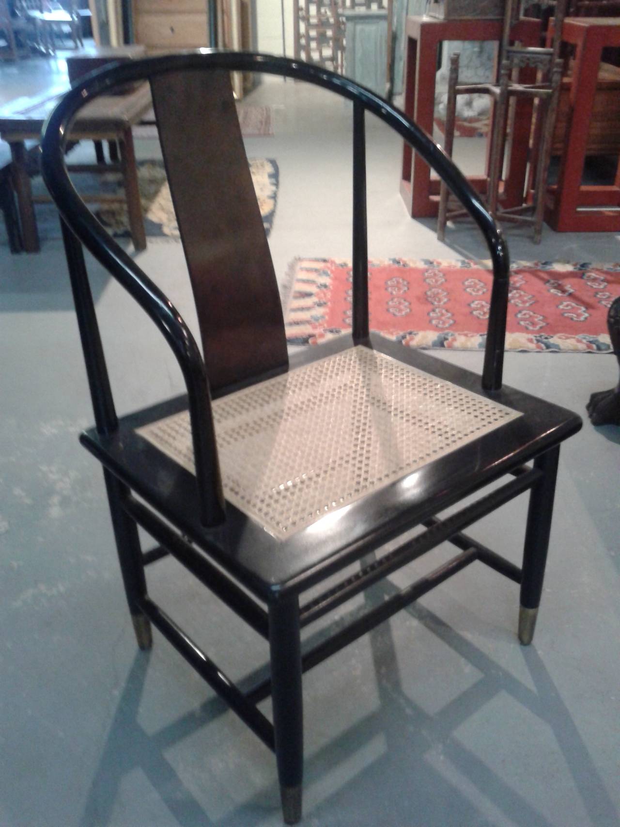 Black lacquer Mid-Century cane bottom horseshoe style chair with a flair of Asia. Excellent condition with brass feet. Nice lines, circa 1955.
