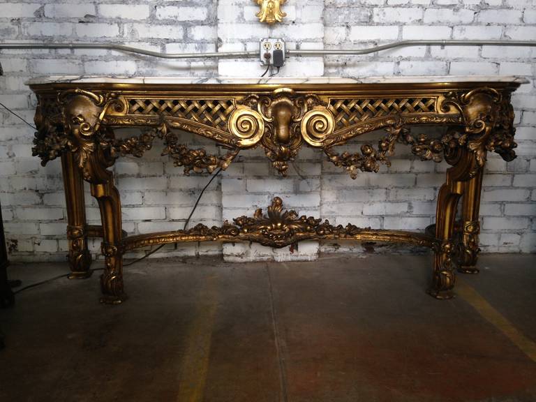 Beautiful French 1900s Louis XV-style marble-top gilt console. This piece has a fabulously beautiful French 1700s beveled marble top. The hand-carved gilt solid wood frame has flowers and leaves. There is a carved garland of flowers which hangs from