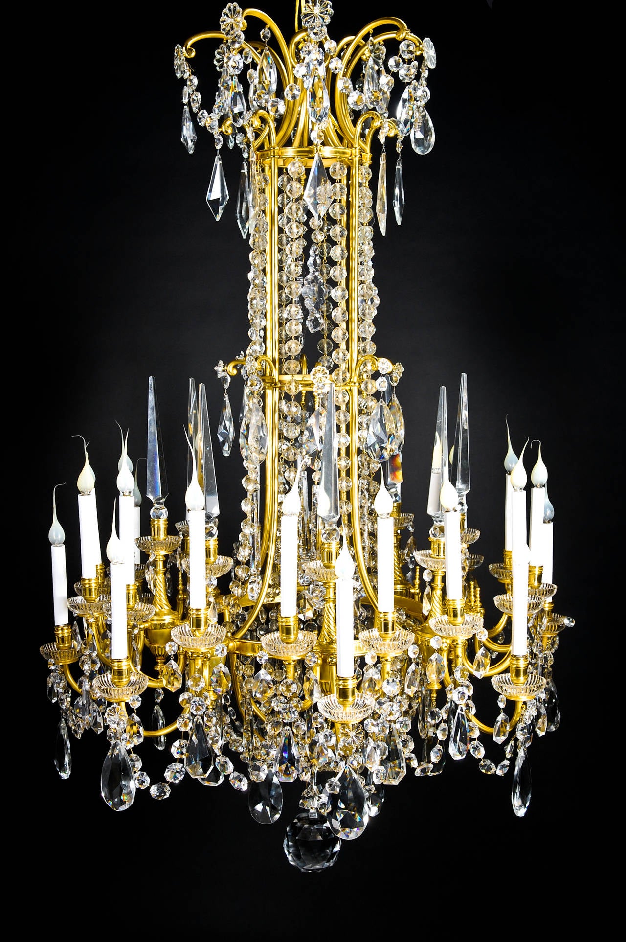 Un spectaculaire et grand lustre ancien français de style Louis XVI, en bronze doré et cristal taillé, à trois niveaux et à plusieurs lumières, embelli par des bobeches en verre, des chaînes en cristal taillé et orné de prismes en cristal taillé de