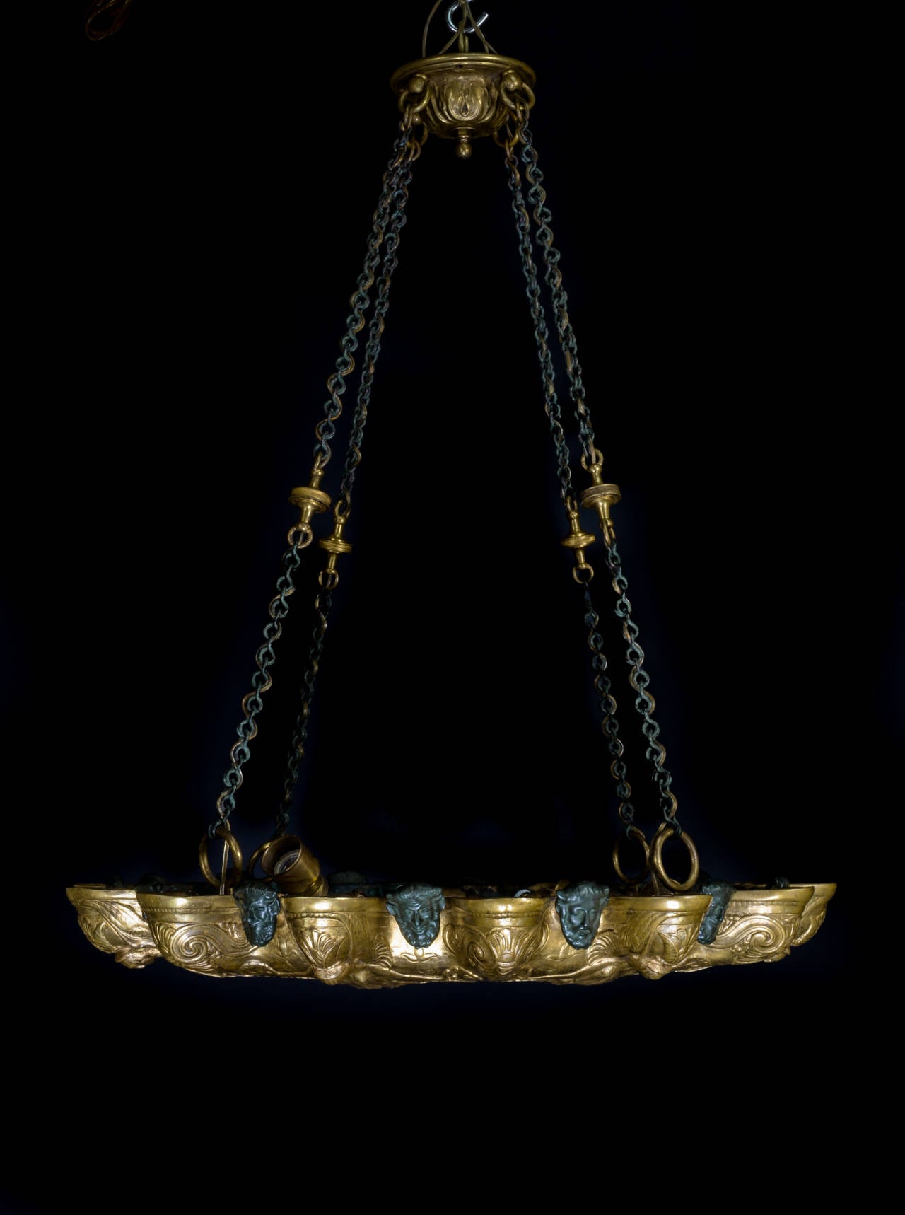 A Unique Antique American Neoclassical Gilt & Patinated Bronze multi light dish chandelier embellished with figural masks, neoclassical motifs & finally adorned with a central plaque, By E.F. Caldwell.