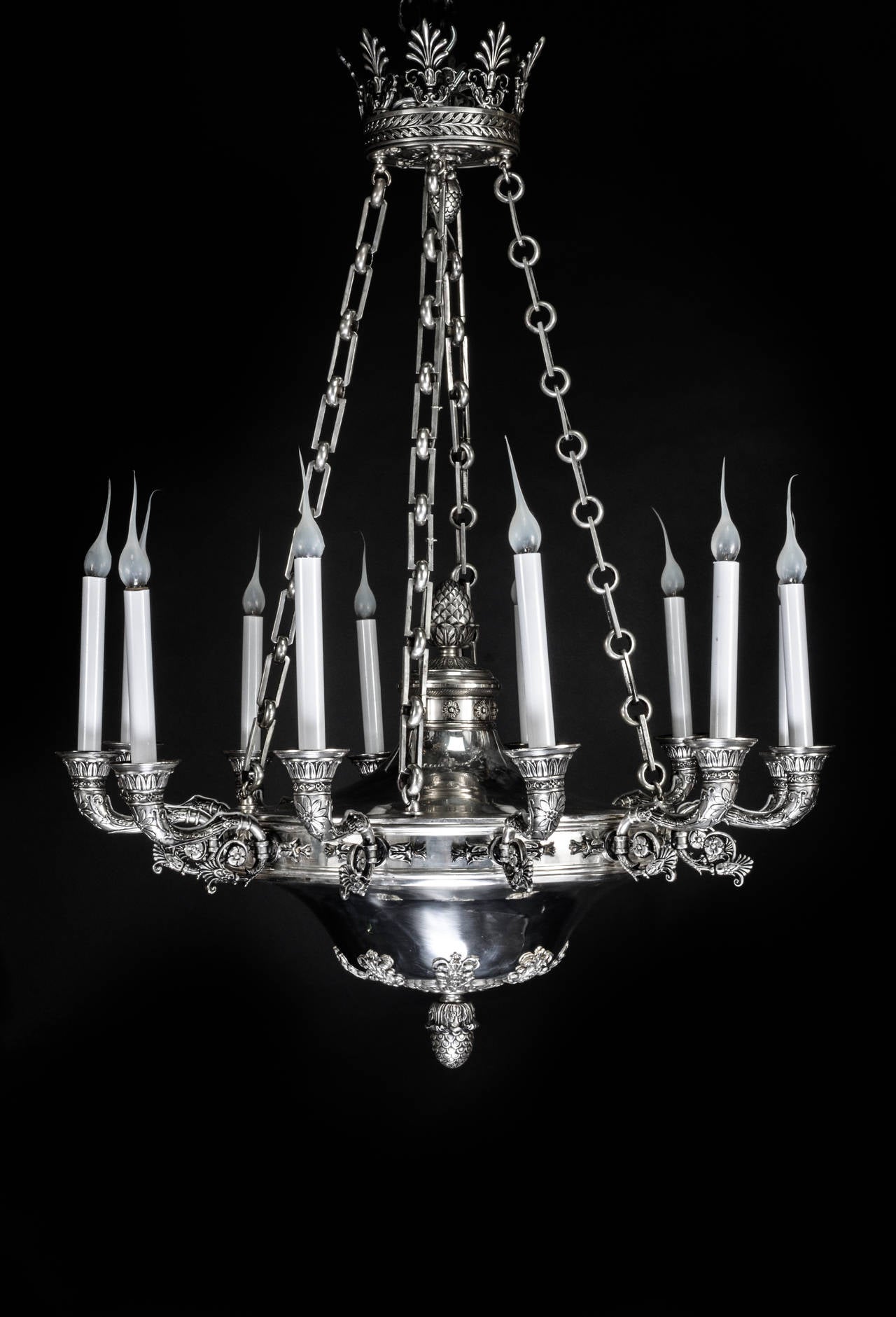 A large antique French Empire style silvered bronze multi light chandelier embellished with neoclassical motifs.
